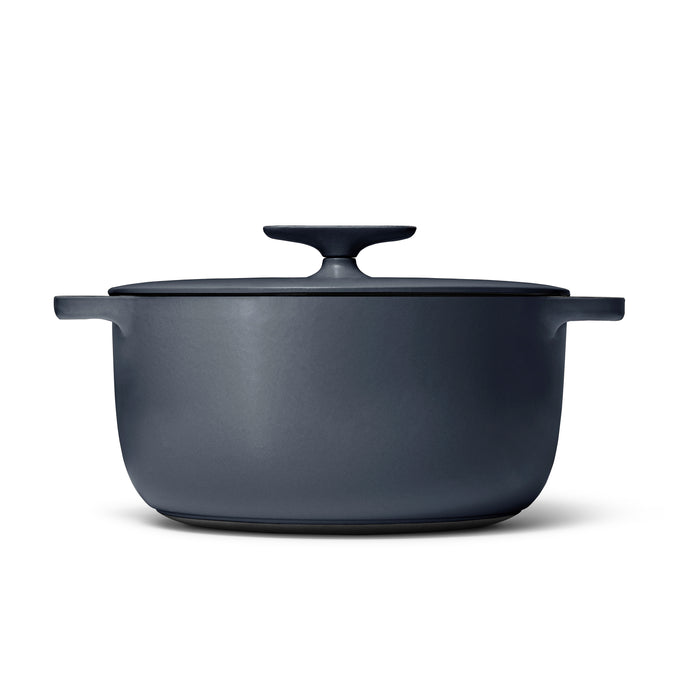 The Caraway Cast Iron Dutch Oven with Flat Lid, 6.5 qt, in matte black boasts a sleek design and includes a round handle lid and two side handles for superior heat retention. Its non-toxic material makes it ideal for safe and efficient cooking.