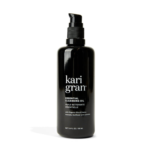 The 3.4 fl. oz. black pump bottle of Kari Grans Essential Cleansing Oil features organic oils like avocado, sunflower, and lavender for a hydrating cleanse and effective makeup removal.