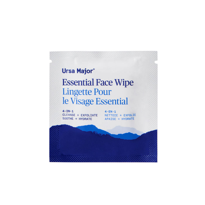 An individually wrapped Ursa Major Essential Face Wipe packet with blue mountain graphics and bilingual English/French text offers 4-in-1 action: cleanse, exfoliate, soothe, and hydrate with bamboo facial wipes.