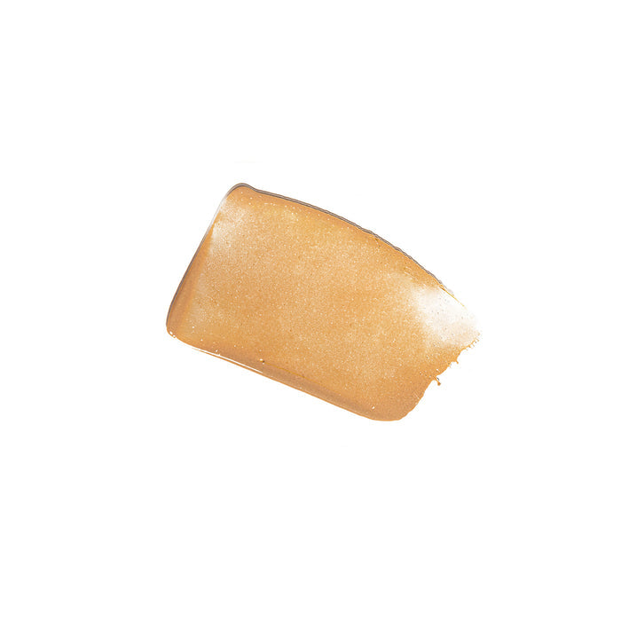 A swatch of Kari Grans Essential Tinted SPF 30, a creamy golden beige mineral sunscreen with a smooth texture and glossy, shimmery finish infused with red raspberry seed oil. It appears shaped like a soft-edged rectangle against a plain white background.