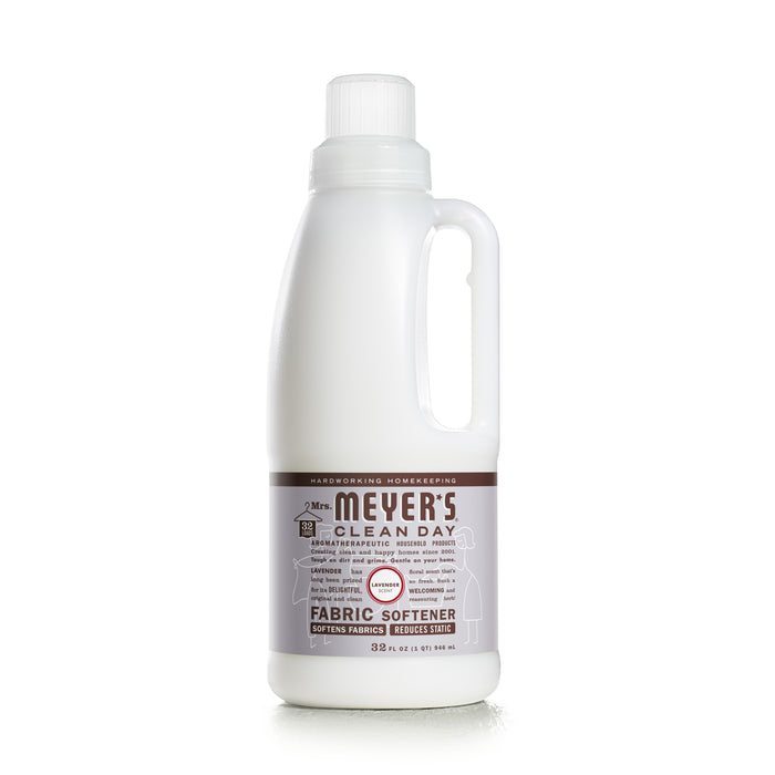 A white 32 fl oz Mrs. Meyers Fabric Softener bottle, featuring a side handle and brown label with white text, showcases its essential oil blend for softening fabrics and reducing static.