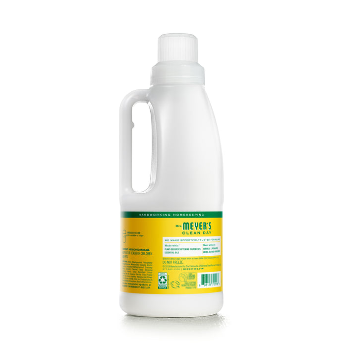 A plastic bottle of Mrs. Meyers Fabric Softener, a laundry essential with a white body and yellow label. Infused with essential oils, it has a side handle and white cap. The label details features and usage instructions.