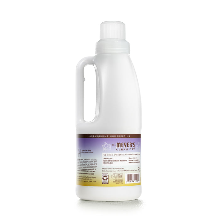 Mrs. Meyers Fabric Softener, an essential for the laundry room, comes in a white plastic bottle with a side handle and a purple label. The label features small lavender illustrations, reflecting its soothing lavender scent enriched with essential oils.