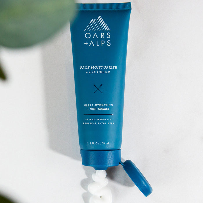 A blue tube of Oars + Alps Face + Eye Cream is shown with the cap open and a swirl of white cream. This ultra-hydrating, non-greasy, fragrance-free formula helps boost skin elasticity.