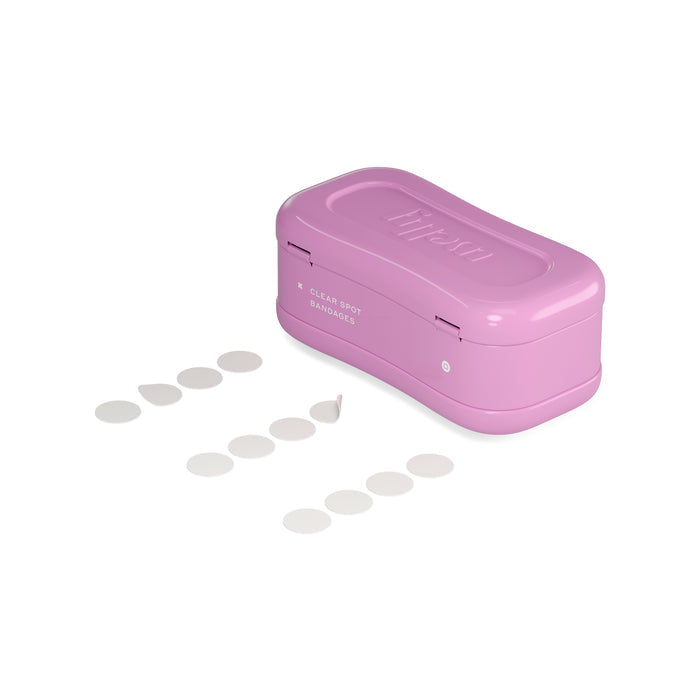 A pink rectangular container with Hero embossed on the lid sits next to several small circular Welly Face Saver bandages, with one partially peeled off, arranged in two neat rows.