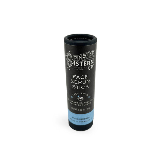 A black cylindrical tube labeled Spinster Sisters Co. Face Serum Stick showcases a formula free of parabens, sulfates, and phthalates. It contains hyaluronic acid, blue tansy oil, and vitamins, with packaging weighing 0.5 oz or 15 g.
