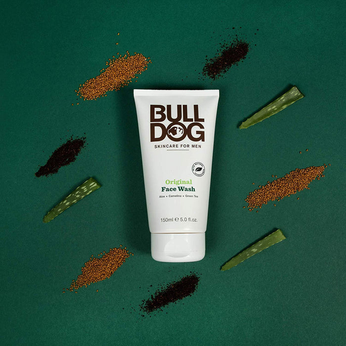 The image showcases a Bulldog Face Wash tube set against a dark green background, surrounded by aloe leaves and brown seeds, emphasizing its natural ingredients and commitment to cruelty-free skincare.