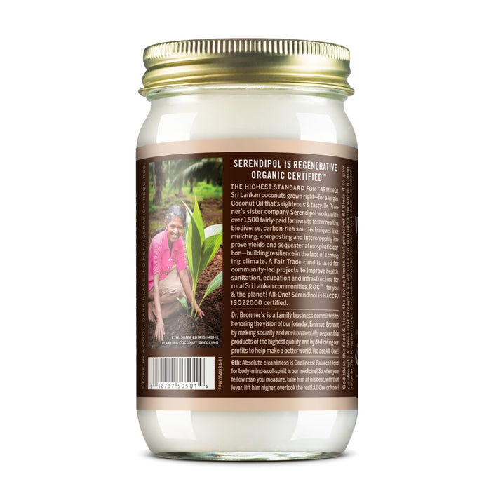 A glass jar of Dr. Bronners Fair Trade & Organic Whole Kernel Virgin Coconut Oil with a brown label showing certification details and a photo of someone kneeling by a young coconut plant in a garden.