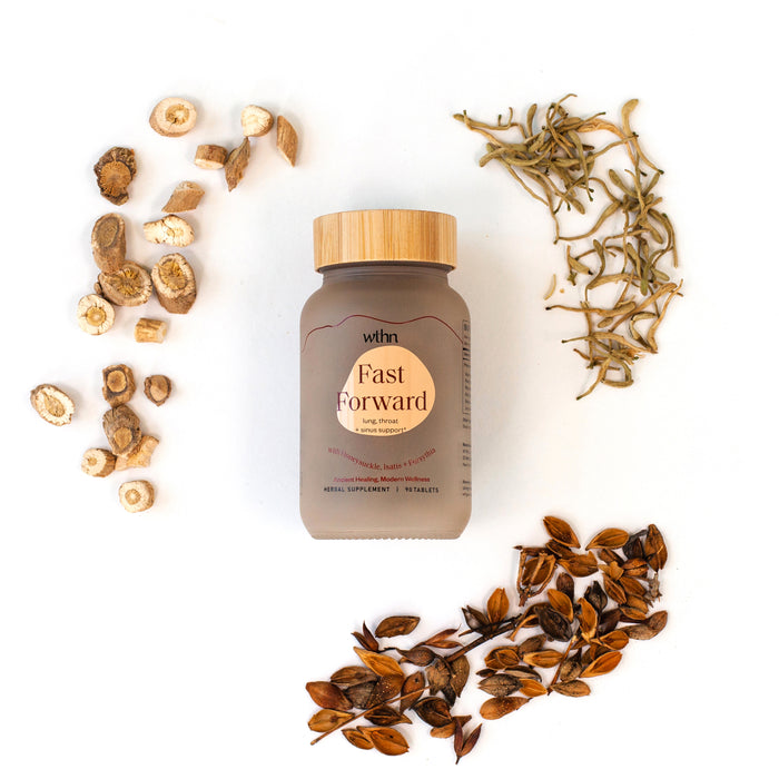 The WTHN Fast Forward bottle, capped with wood, sits on a white background encircled by three clusters of dried herbs and roots, suggesting an anti-viral Chinese formula for an enhanced immune response.