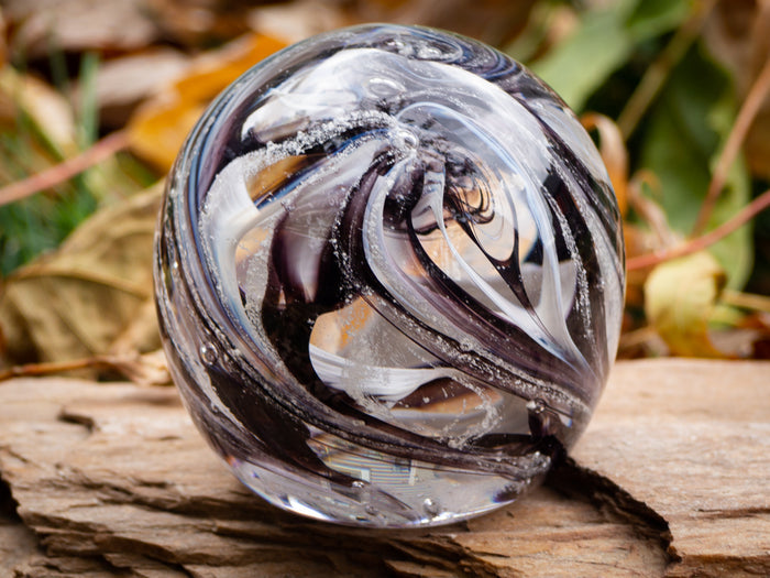 Feather patterned cremation ash orb with a flat bottom for stable display.