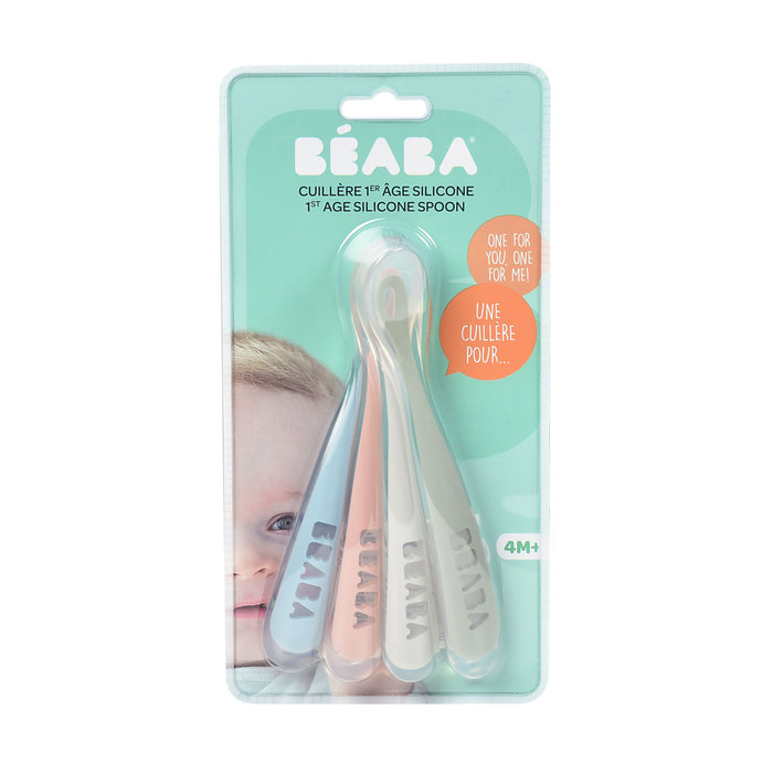 A pack of BEABA First Foods Silicone Spoons includes pink, blue, and gray spoons for babies 4 months and older. The package has a partial baby image and bilingual English-French text.