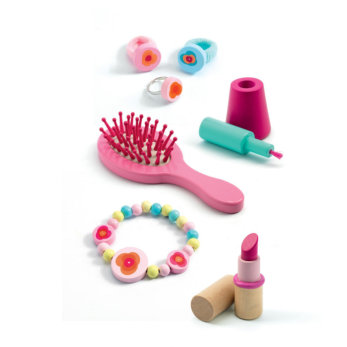The DJECO Flora Dressing Table Play Set includes creative toys like a pink hairbrush, lipstick, blue nail polish bottle, colorful bead bracelet, and flower-themed rings and hairbands. Made from 100% FSC® Certified Wood with non-toxic materials.