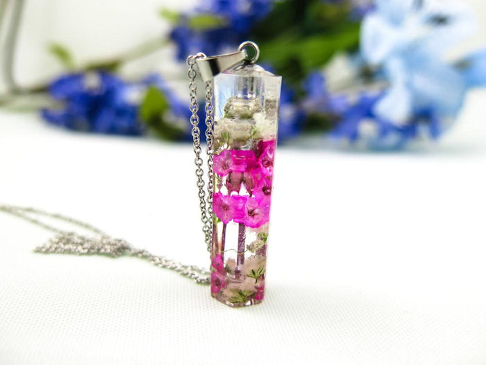 Crystal resin pendant with pink blossoms embedded inside on a stainless steel chain