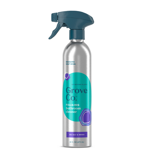 The Grove Co. Foaming Bathroom Cleaner, in an 18 fl oz (475 mL) recyclable aluminum spray bottle with a teal and purple label and blue nozzle, features a sea salt and neroli scent that enhances the multi-purpose formula to effectively dissolve soap scum.