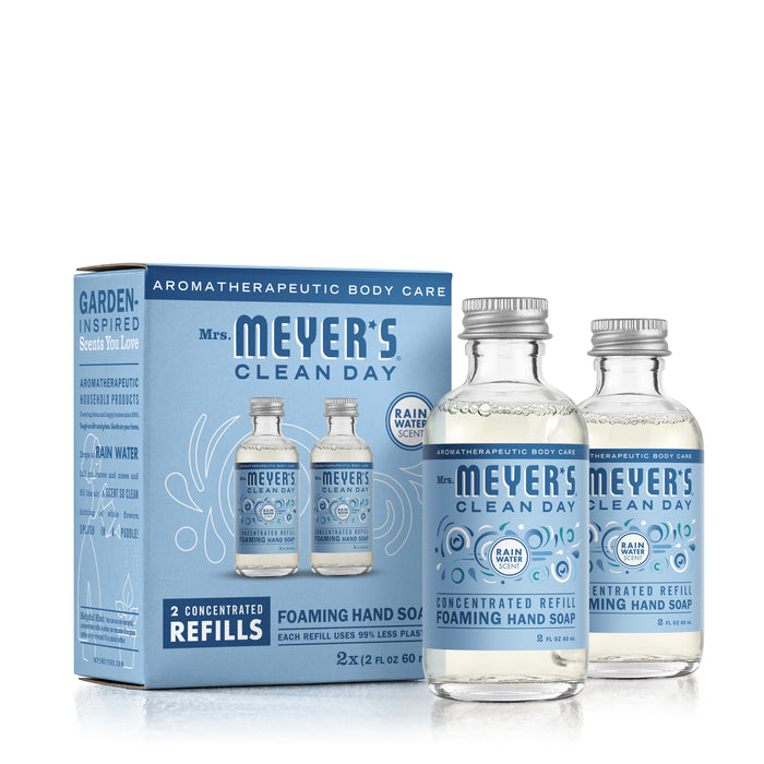 Mrs. Meyers Foaming Hand Wash Concentrate Refills include a box with two refill bottles, each 2 fl oz (60 ml), in Rain Water scent. Featuring aromatherapeutic body care and eco-friendly packaging, it highlights reduced plastic use and natural cleaning agents.