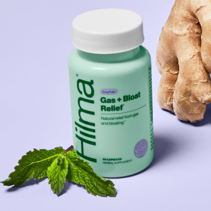 A mint-green bottle of Hilma Gas + Bloat Relief rests on a light purple surface beside fresh mint leaves and ginger root, highlighting the natural herbs that gently support digestion.