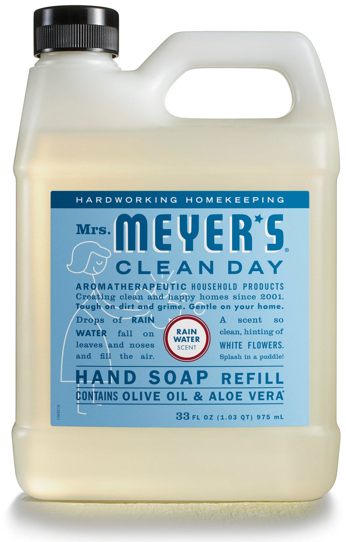 A 33 fl oz (975 ml) plastic bottle of Mrs. Meyers Gel Hand Soap Refill in Rain Water scent, enriched with essential oils, olive oil, and aloe vera. This cruelty-free product has a handle for easy pouring and a beige label with blue and white text.