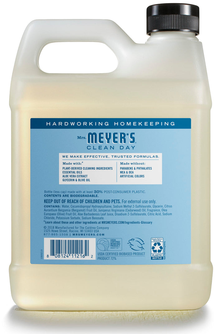 A clear bottle of Mrs. Meyers Gel Hand Soap Refill highlights eco-friendly, plant-based ingredients and essential oils with a free-from-parabens, cruelty-free formula. The blue label reveals the yellow liquid and emphasizes its biodegradable content.