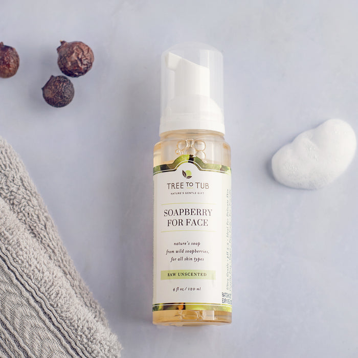 Tree To Tubs Gentle Face Wash for Sensitive Skin with Raw Unscented is a 4 fl oz foaming face cleanser ideal for fragrance-free use. Displayed on a light surface with a gray towel, soapberries, and a white stone, it’s perfect for sensitive skin.