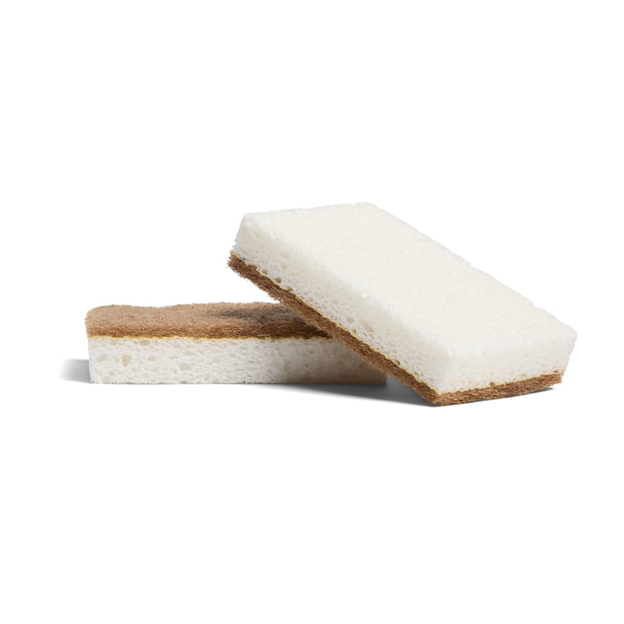 Two Grove Co. Walnut Scrubber Sponges, each with a soft white plant-based cellulose side and a brown scouring side made with walnut shells, are stacked together against a white background.