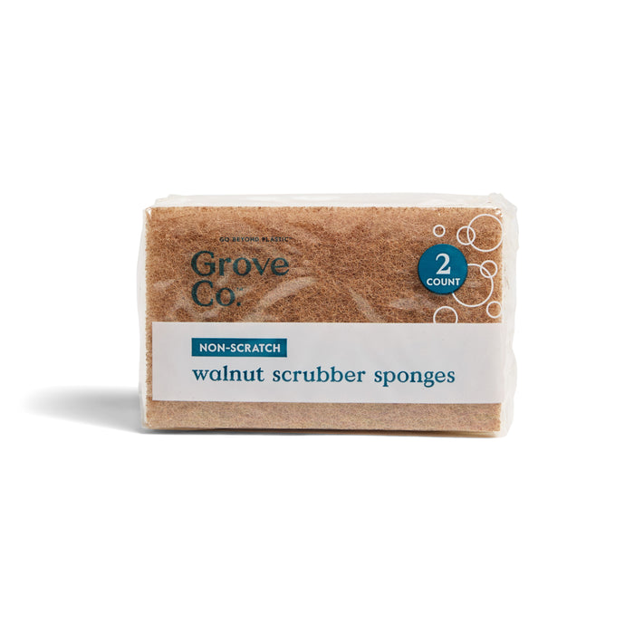 A pack of Grove Co. Walnut Scrubber Sponges, made from plant-based cellulose and walnut shells, labeled non-scratch, with two sponges displayed in clear packaging featuring the Grove Co. branding on the front.