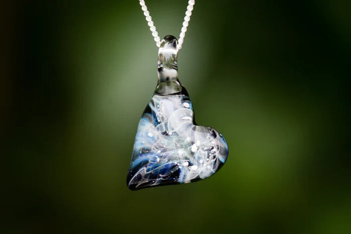 Close up of a heart shaped Ghost glass pendant infused with cremation ashes on a silver chain