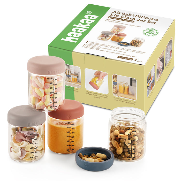 Haakaas Glass Baby Food Storage Jar Set includes three airtight silicone lid jars ideal for baby food or homemade meals. The jars are shown with marshmallows, orange puree, and mixed nuts, featuring lids in beige, orange, and dark gray with box packaging in the background.