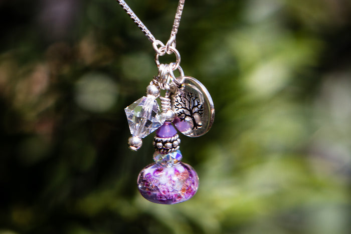 Adjustable necklace featuring a cremation ash infused glass bead with crystal accents and silver charms
