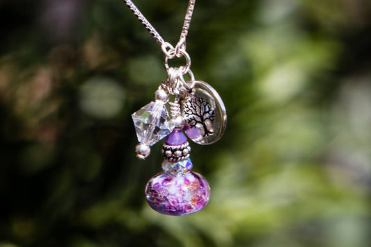 Adjustable necklace featuring a cremation ash infused glass bead with crystal accents and silver charms
