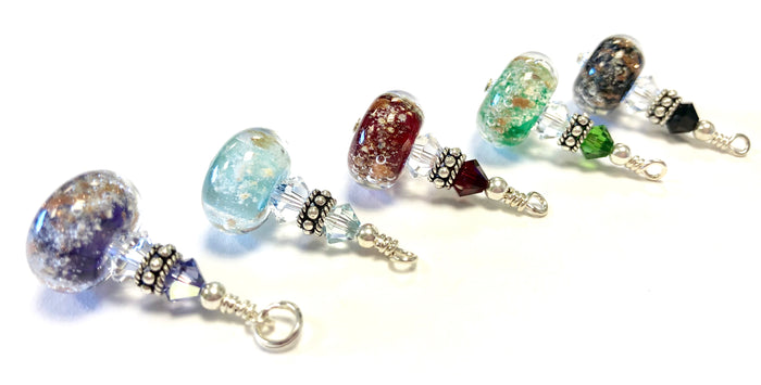 Colorful glass beads infused with cremains, separated by crystal spacers and silver end caps on a necklace segment.