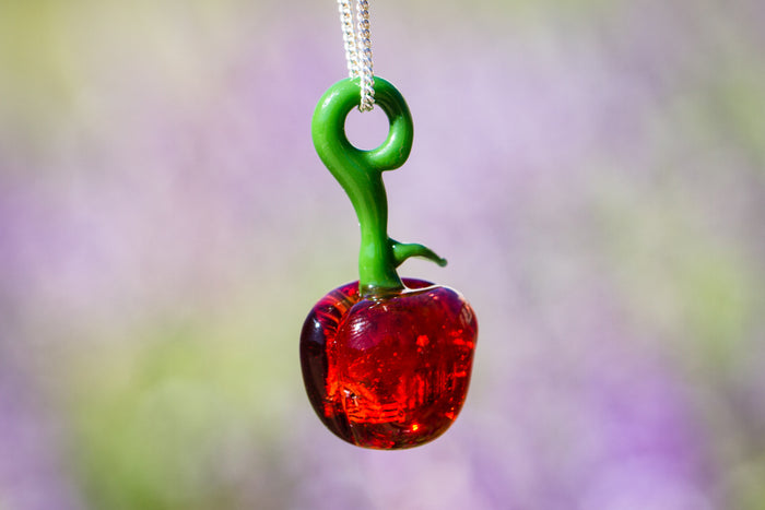 Glass cherry pendant infused with cremation ash featuring a green stem and red fruit on a silver chain.