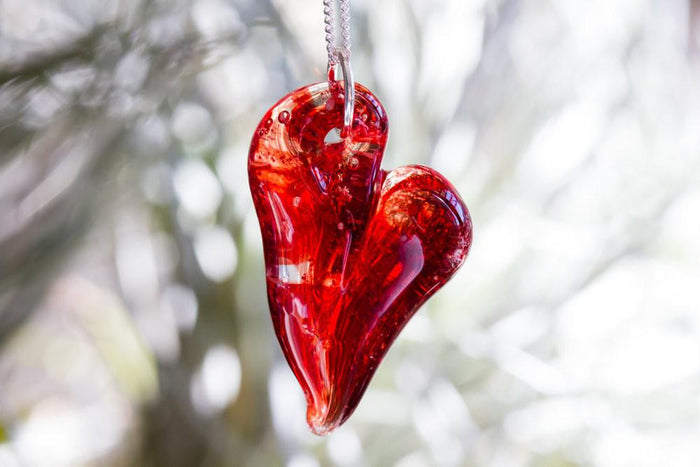 Red glass heart cremation pendant on a silver chain with ashes infused inside
