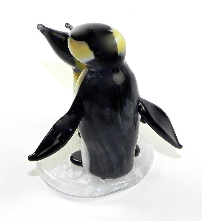 Back view of a single glass penguin figurine with cremation ashes on a white base
