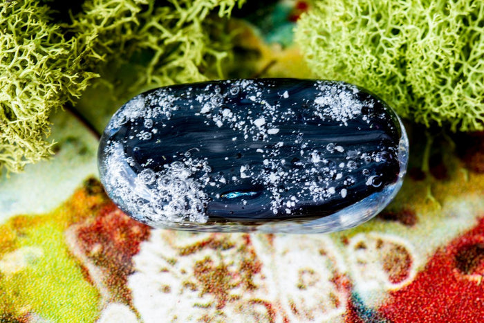 Dark black glass sparkle stone with white bubbly specks against a colorful background