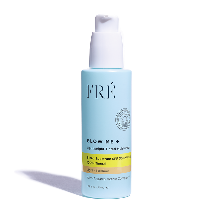 A blue pump bottle of FRÉ Skincares GLOW ME + Tinted Mineral SPF 30 Moisturizer, featuring Argania Active Complex™, offers light-medium Broad Spectrum UVA/UVB protection. Capacity: 1.69 fl oz (50mL).