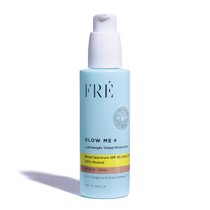 FRÉ Skincares GLOW ME + Tinted Mineral SPF 30 Moisturizer in light blue features a white pump dispenser and the nourishing Argania Active Complex™. The label highlights its broad spectrum sunscreen suitable for medium to deep skin tones.