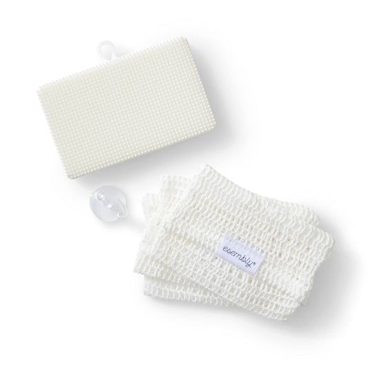 A neatly arranged set of bath items on a white background, featuring a textured rectangular sponge, mesh washcloth with an esembljr tag, and a suction cup hook—all part of the GoTwo™ Kitchen Sponge Set by Esembly Baby.