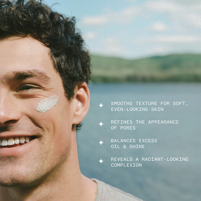 A smiling man outdoors by a lake wears Ursa Major’s Green Slate Mineral Polish, with white cream on his cheek. Text lists benefits: smooths and re-texturizes skin, refines pores, balances oil and shine, reveals radiance.