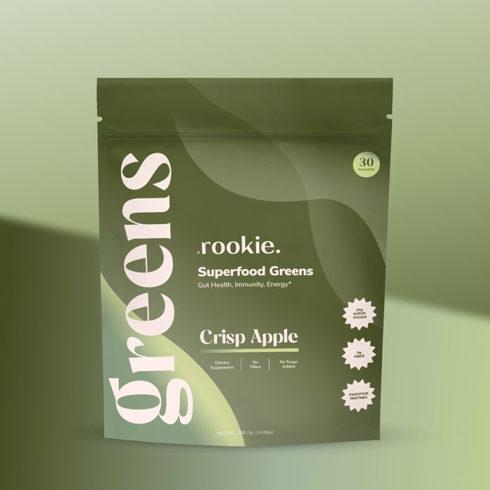 A green Rookie Wellness pouch labeled Greens + Superfood in Crisp Apple flavor supports gut health and immunity with daily greens and probiotics, offering energy benefits in 30 servings. "Greens" is written vertically on the pouch.