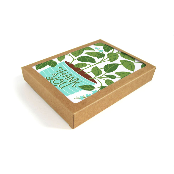 The Neighborgoods Greeting Cards set arrives in a recyclable brown cardboard box featuring an original thank you card with lush plant artwork and Thank You scripted elegantly on a blue background.