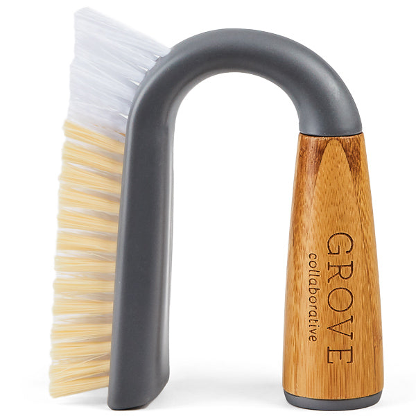 The Grunge Buster Grout & Tile Brush by Grove Co. has a curved handle partly made of light wood with GROVE collaborative etched on it. Its tough, two-tone bristles—white outside and beige inside—are ideal for efficient tile cleaning.