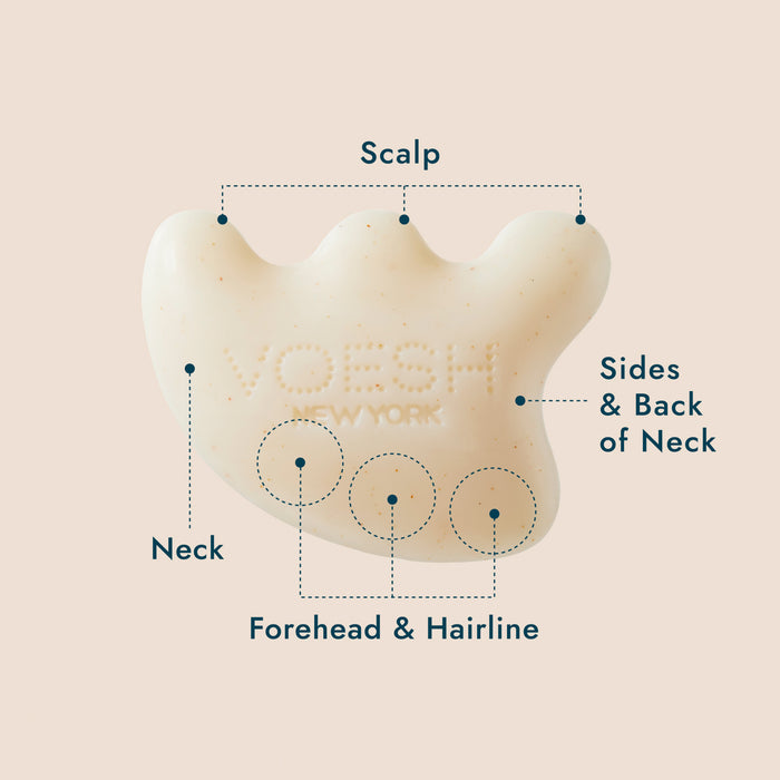 A white, uniquely shaped massage tool with the brand name "VOESH NEW YORK" embossed on it. The tool has four smooth rounded points and is labeled for use on the scalp, sides and back of the neck, neck, forehead, and hairline.