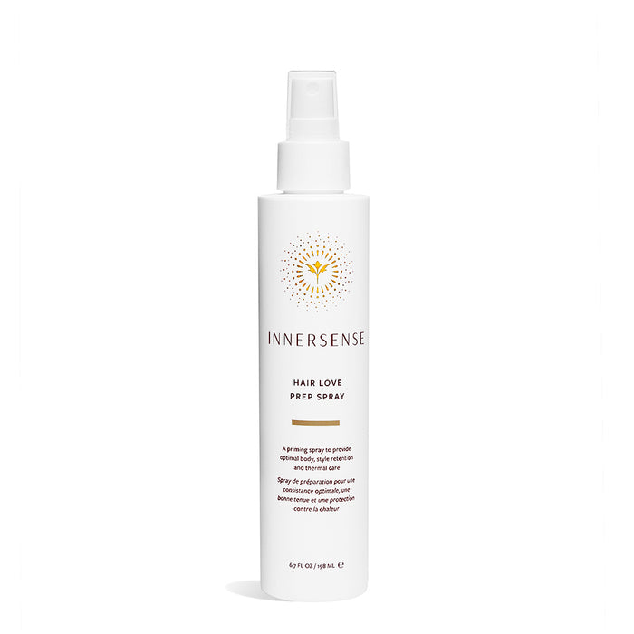 The Hair Love Prep Spray by Innersense Organic Beauty is in a white bottle with a spray nozzle, featuring a minimalist design. The packaging includes product information and a yellow sunburst logo above the brand name, enriched with organic aloe vera for nourishing care.