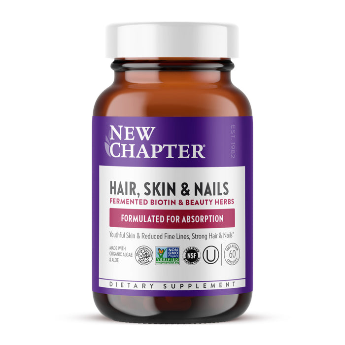 A brown glass bottle of New Chapters Hair Skin & Nails supplement features a purple and white label with red text, emphasizing its enhanced absorption formula. It contains fermented biotin and beauty herbs to improve skin elasticity and holds 60 capsules.