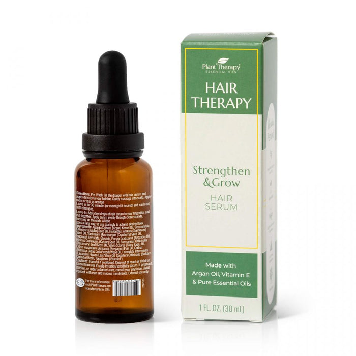 A brown dropper bottle labeled Plant Therapy Hair Therapy Strengthen & Grow Hair Serum sits beside its box, highlighting botanical ingredients like argan oil, vitamin E, and essential oils. The 1 fl. oz. (30 ml) bottle offers nourishing benefits for your hair care routine.