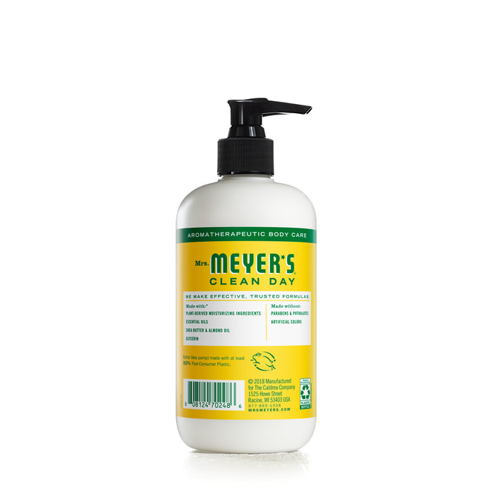 Mrs. Meyers Hand Lotion, enriched with shea butter and essential oils, comes in a pump dispenser. The white label accented with green and yellow offers nourishing care, resting against a white background.