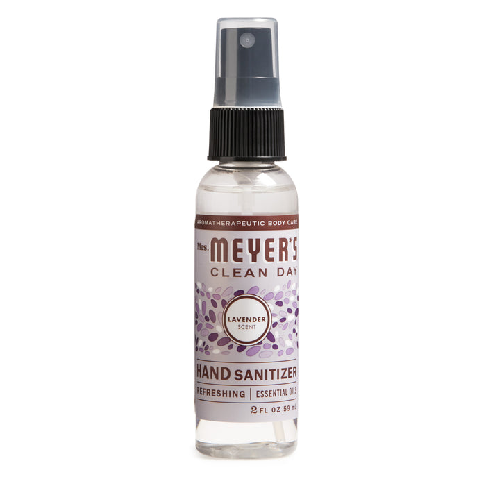 A 2 fl oz (59 mL) spray bottle of Mrs. Meyers Hand Sanitizer with a soothing lavender scent showcases a purple label adorned with lavender illustrations and a dark gray cap, containing 62% ethyl alcohol for effective sanitation.