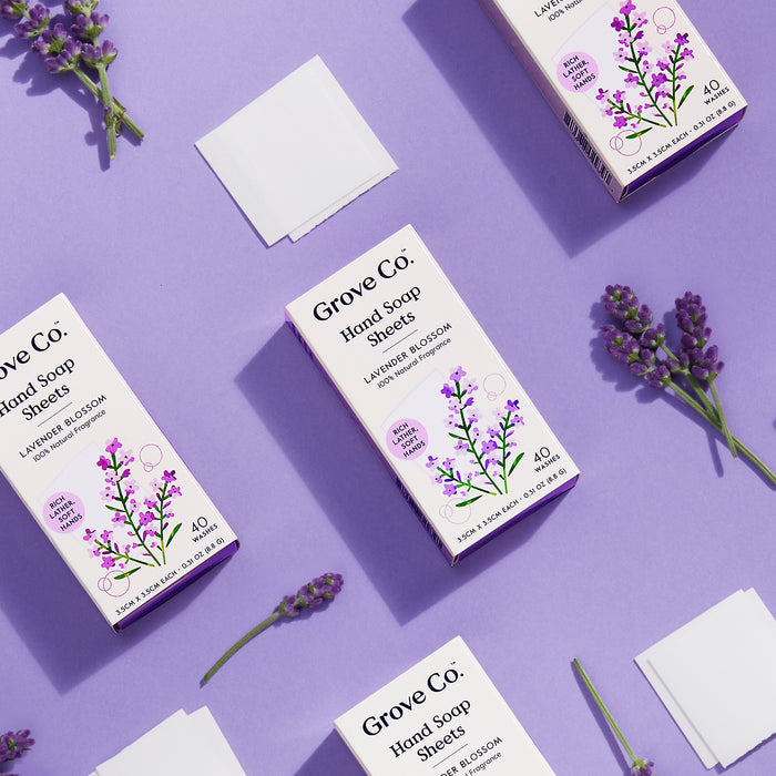 Grove Co. Hand Soap Sheets (40 Washes) are beautifully displayed on a lavender background with fresh sprigs and feature eco-friendly packaging adorned with purple floral illustrations to highlight the natural fragrance.