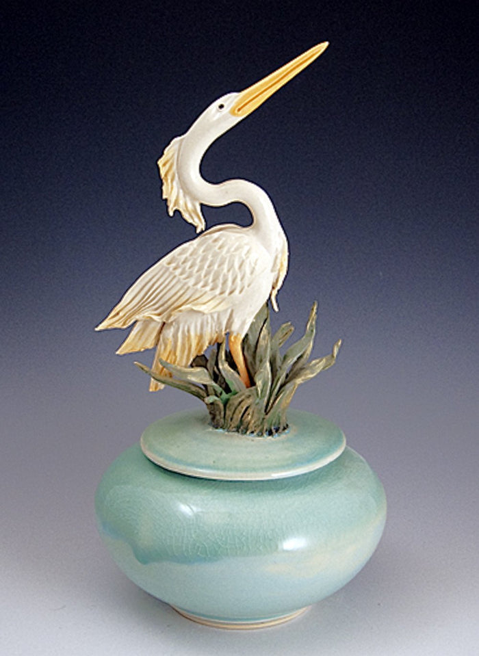 Handmade heron ceramic urn with a white heron perched on a turquoise vase and grass accents.