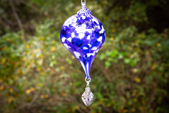 Purple mosaic glass teardrop ornament hanging from a ring with a silver ornate keepsake urn pendant